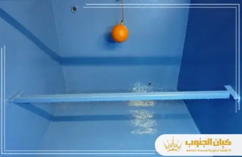 تنظيف خزانات المياه في ابها 0530609402 كيان الجنوب داخل خزان مُعالج باللون الأزرق، تظهر عوامة برتقالية وقضيب دعم أفقي مُغطى بمادة العزل