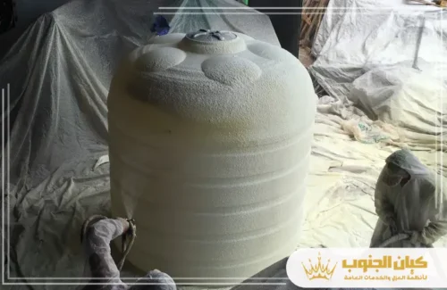 العزل الاسمنتي للخزانات في خميس مشيط 0530609402 كيان الجنوب عامل يرش مادة عازلة بيضاء (مثل البولي يوريثان) على السطح الخارجي لخزان بلاستيكي كبير